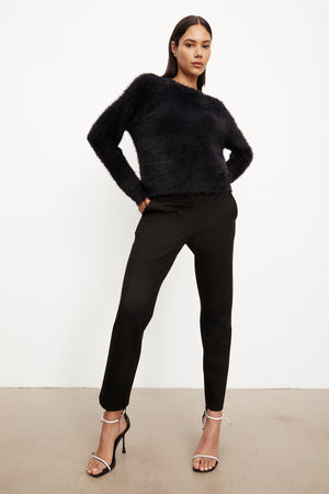 The model is wearing a Velvet by Graham & Spencer RAY FEATHER YARN CREW NECK SWEATER and classic crewneck black trousers.
