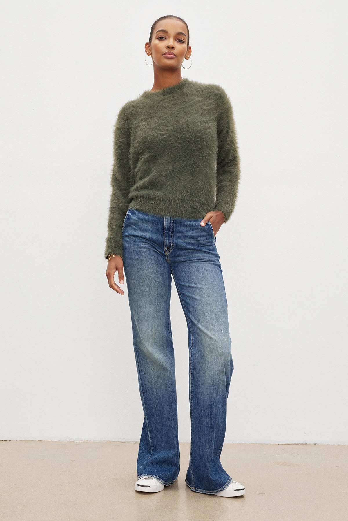 The model is wearing a Velvet by Graham & Spencer RAY FEATHER YARN CREW NECK SWEATER and flared jeans.-35572011434177
