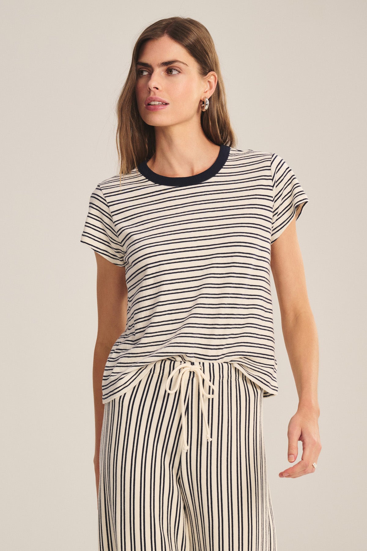 A woman wears the FOSTER TEE by Velvet by Graham & Spencer—a stripe jersey cropped tee featuring a contrast crew neckline—paired with matching drawstring striped pants.-40909835206849