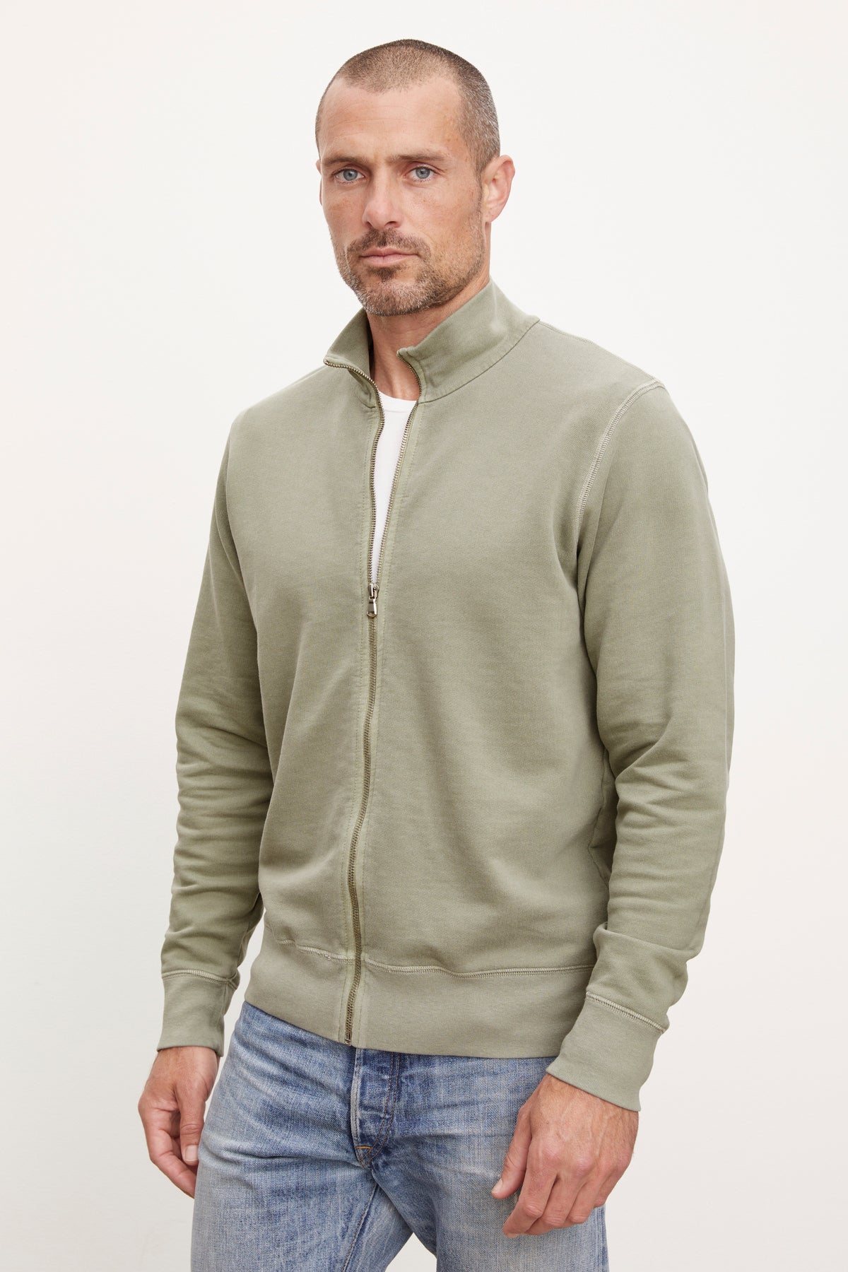   A man wearing a green Velvet by Graham & Spencer TERRY FRENCH TERRY FULL-ZIP sweatshirt and jeans. 