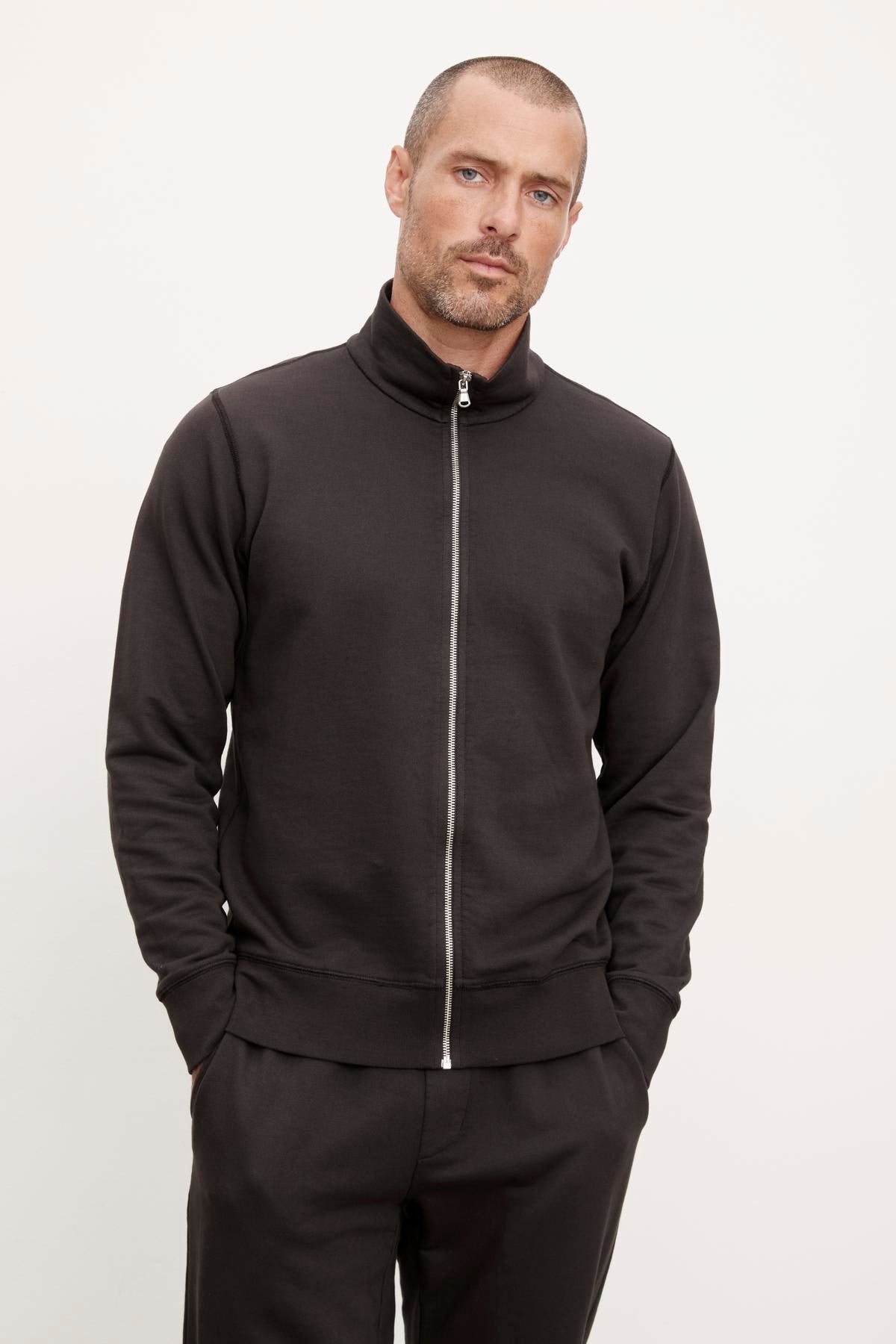 A man wearing a black Velvet by Graham & Spencer TERRY FRENCH TERRY FULL-ZIP sweatshirt from his casual wardrobe.-36008992800961