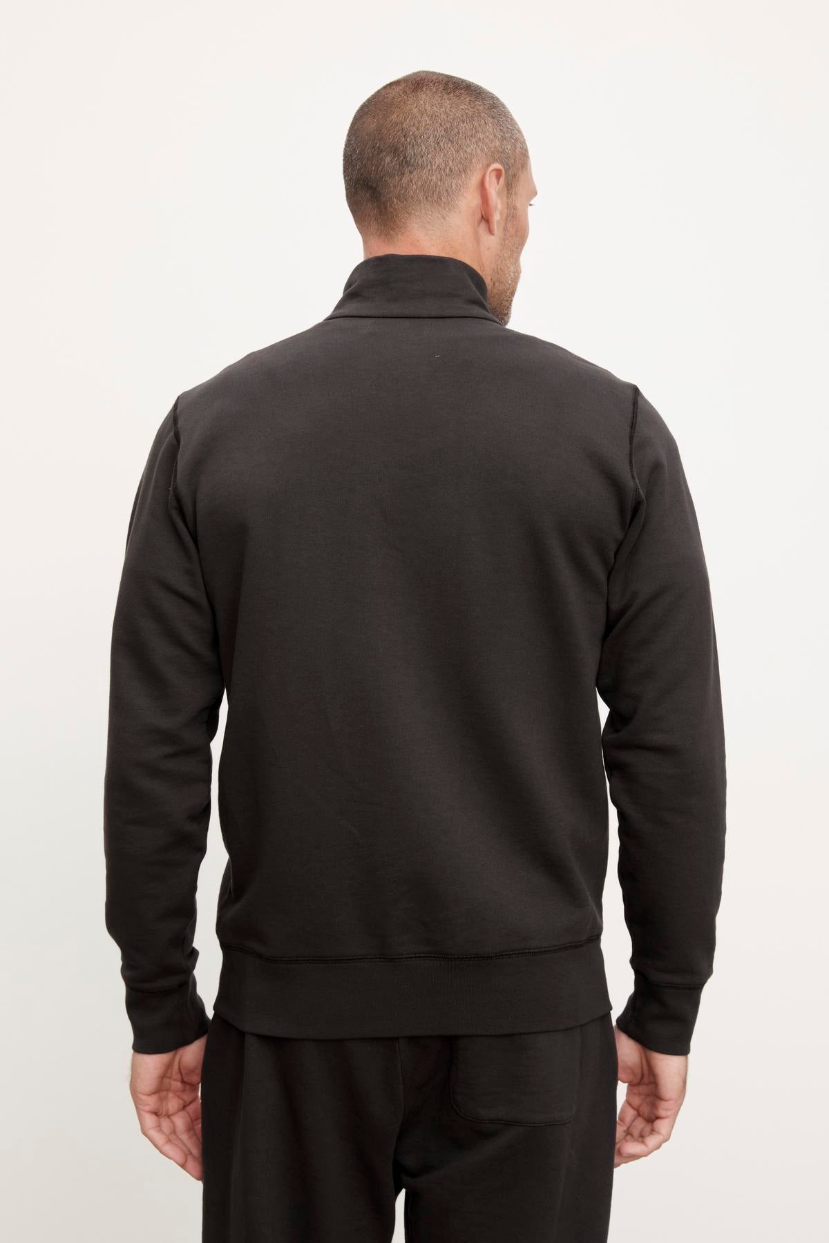 The back view of a man wearing a black Velvet by Graham & Spencer TERRY FRENCH TERRY FULL-ZIP sweatshirt from his casual wardrobe.-36008992899265