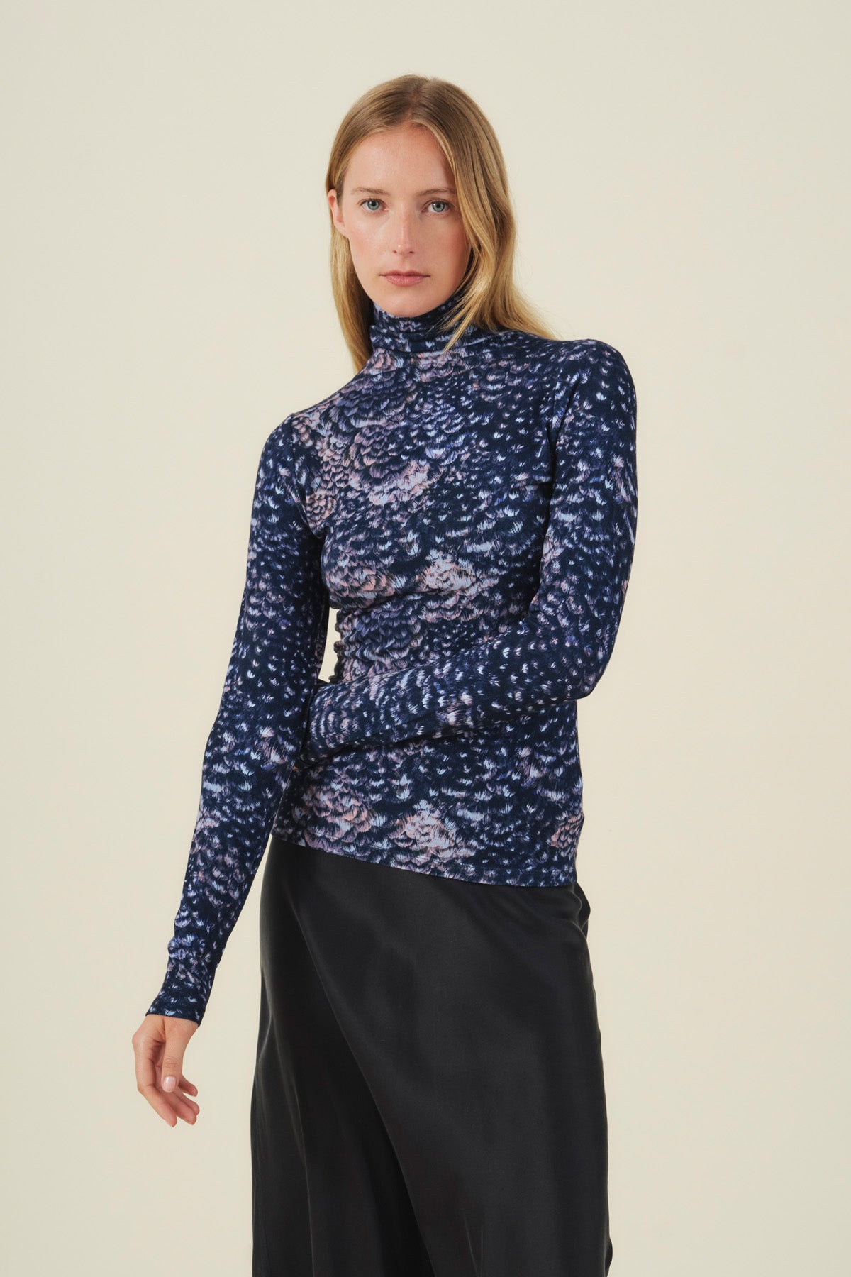 A person wearing a dark blue TAYLOR PRINTED TEE with a blurry, abstract light-colored print and a black skirt.