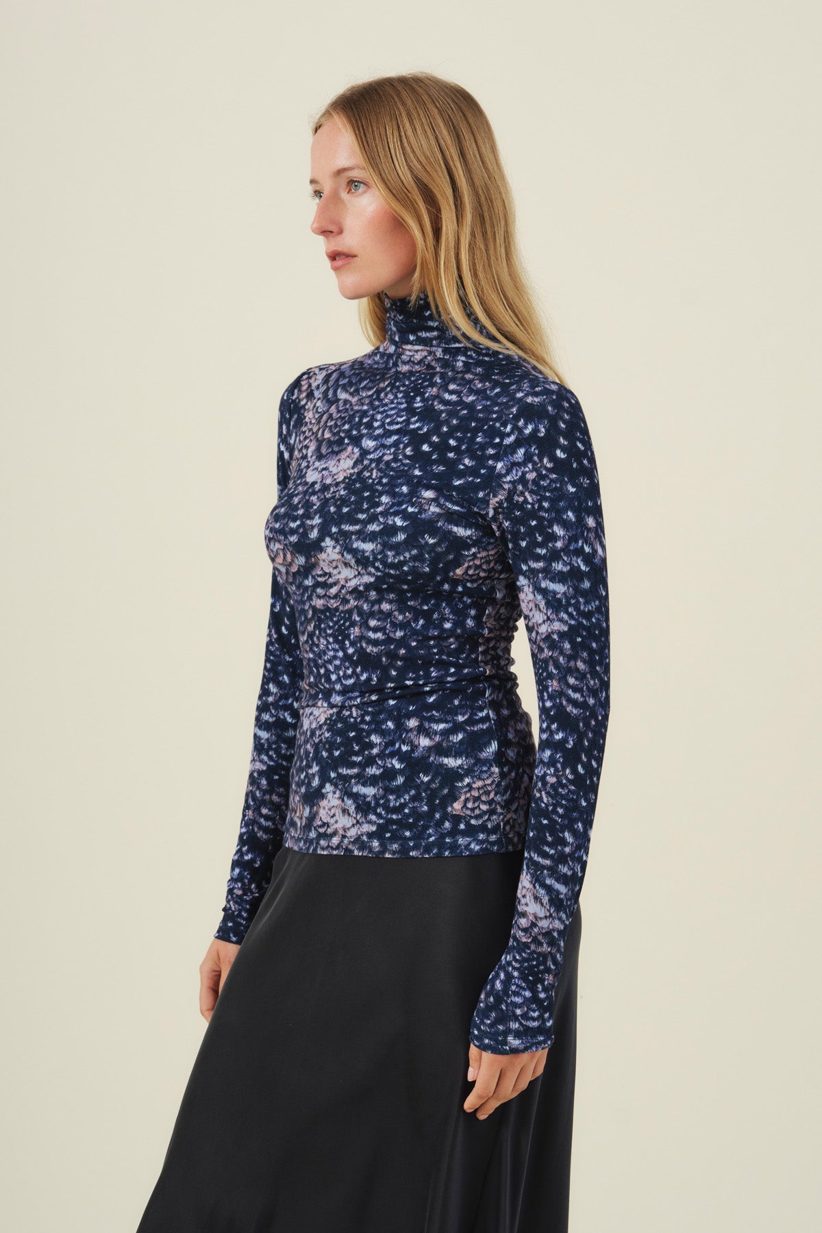 A woman wears the Velvet by Graham & Spencer TAYLOR PRINTED TEE, a long-sleeved, mock neck feather jersey top with a dark, mottled print.-46489712951489