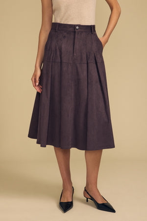A person wears a beige sleeveless top, the BELINDA FAUX SUEDE SKIRT by Velvet by Graham & Spencer— a high-waisted, knee-length pleated skirt—paired with black pointed-toe slingback shoes for an effortlessly chic transitional look.