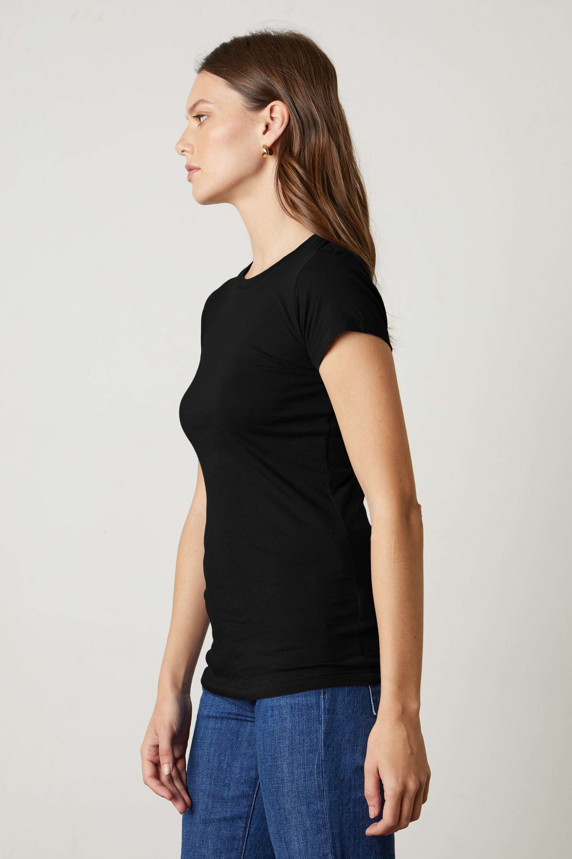   A woman donning a JEMMA GAUZY WHISPER FITTED CREW NECK TEE by Velvet by Graham & Spencer and jeans. 