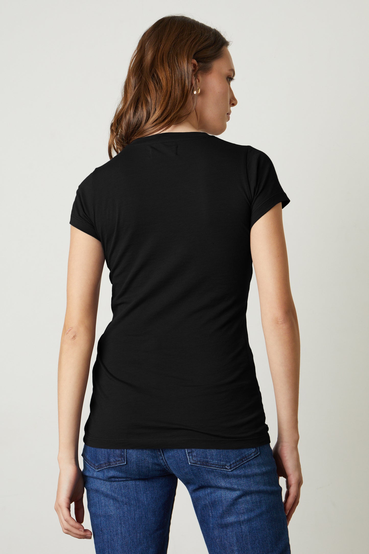 The back view of a woman wearing jeans and a Velvet by Graham & Spencer Jemma Gauzy Whisper Fitted Crew Neck Tee.-35416738267329