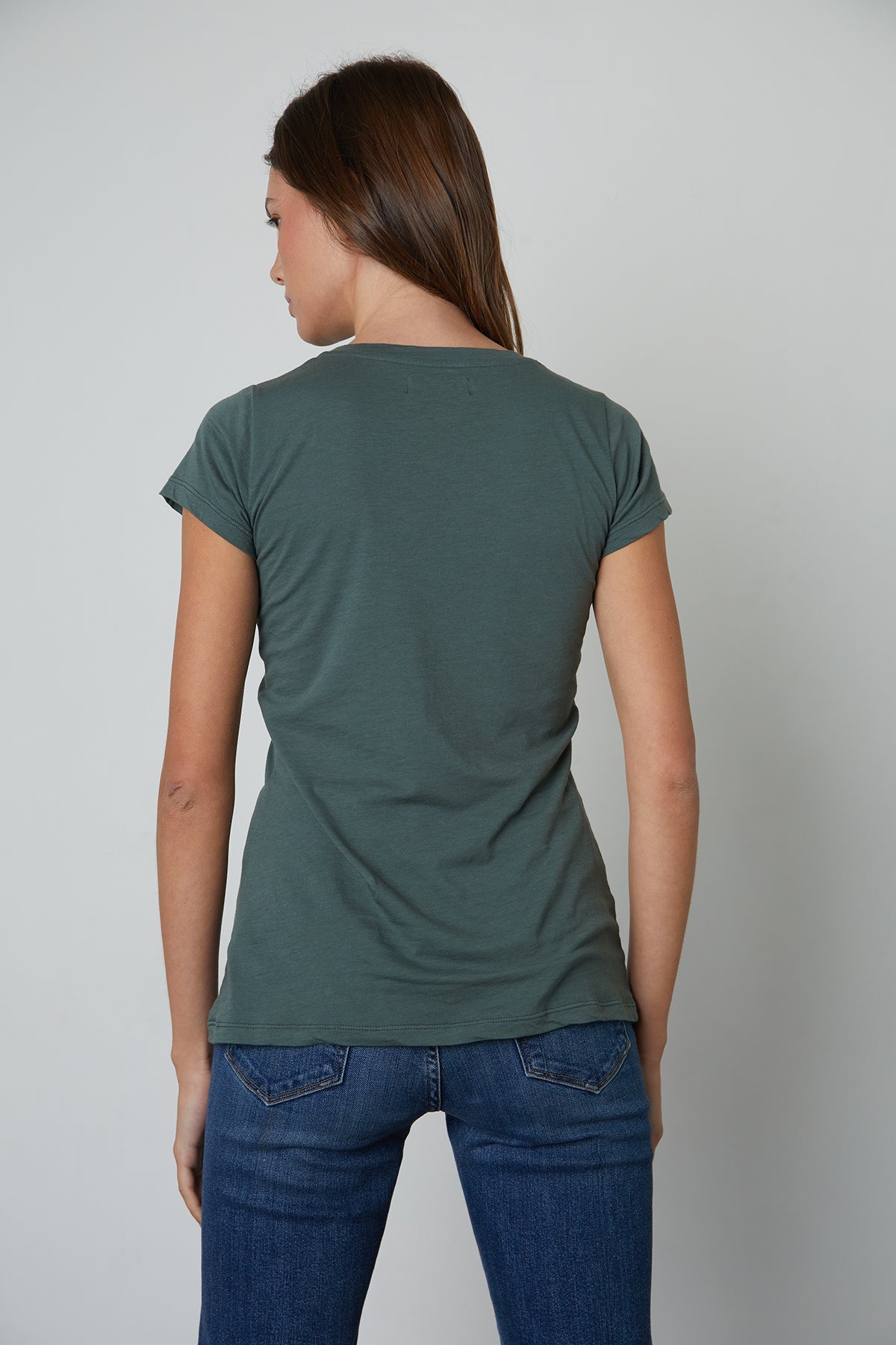 the back view of a woman wearing jeans and a Velvet by Graham & Spencer JEMMA GAUZY WHISPER FITTED CREW NECK TEE.-26630463193281