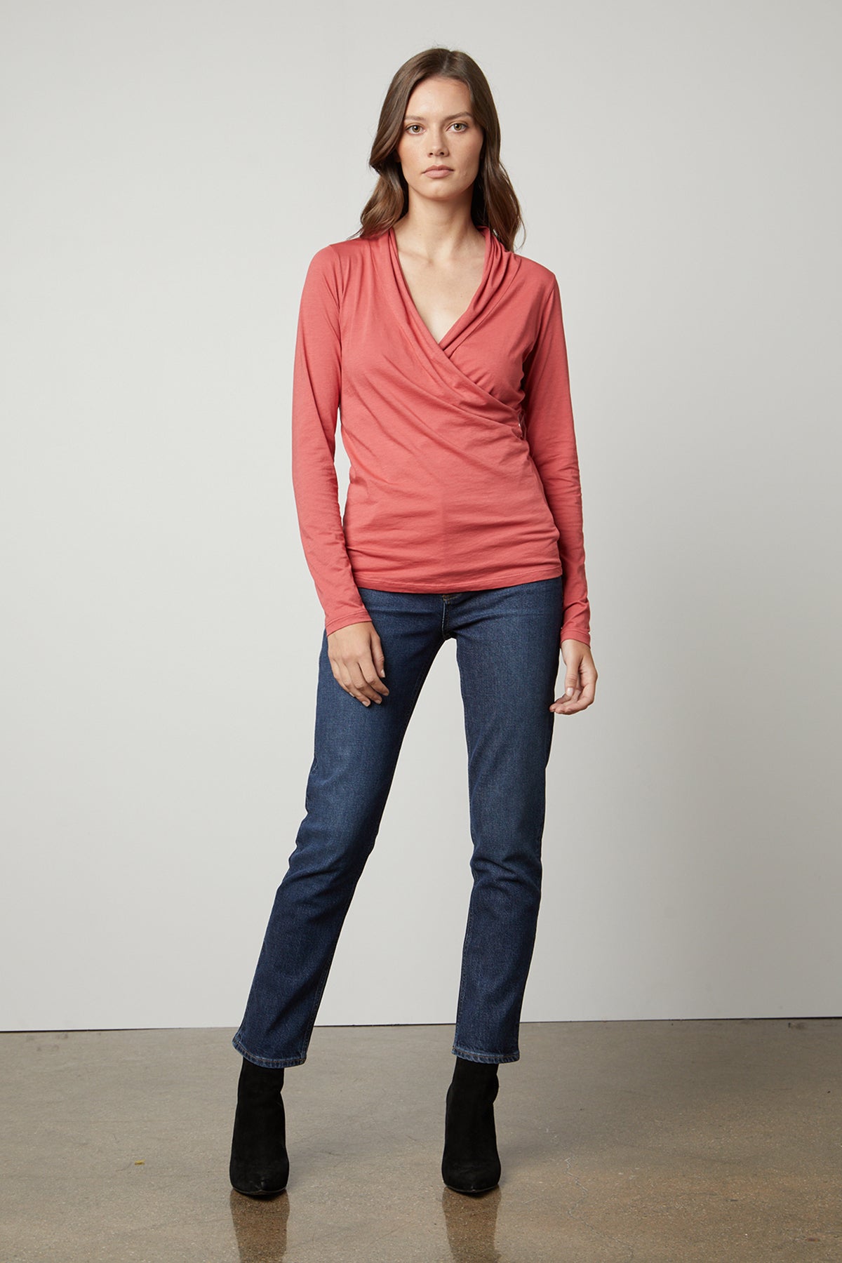   The model is wearing a Velvet by Graham & Spencer MERI WRAP FRONT FITTED TOP and jeans. 