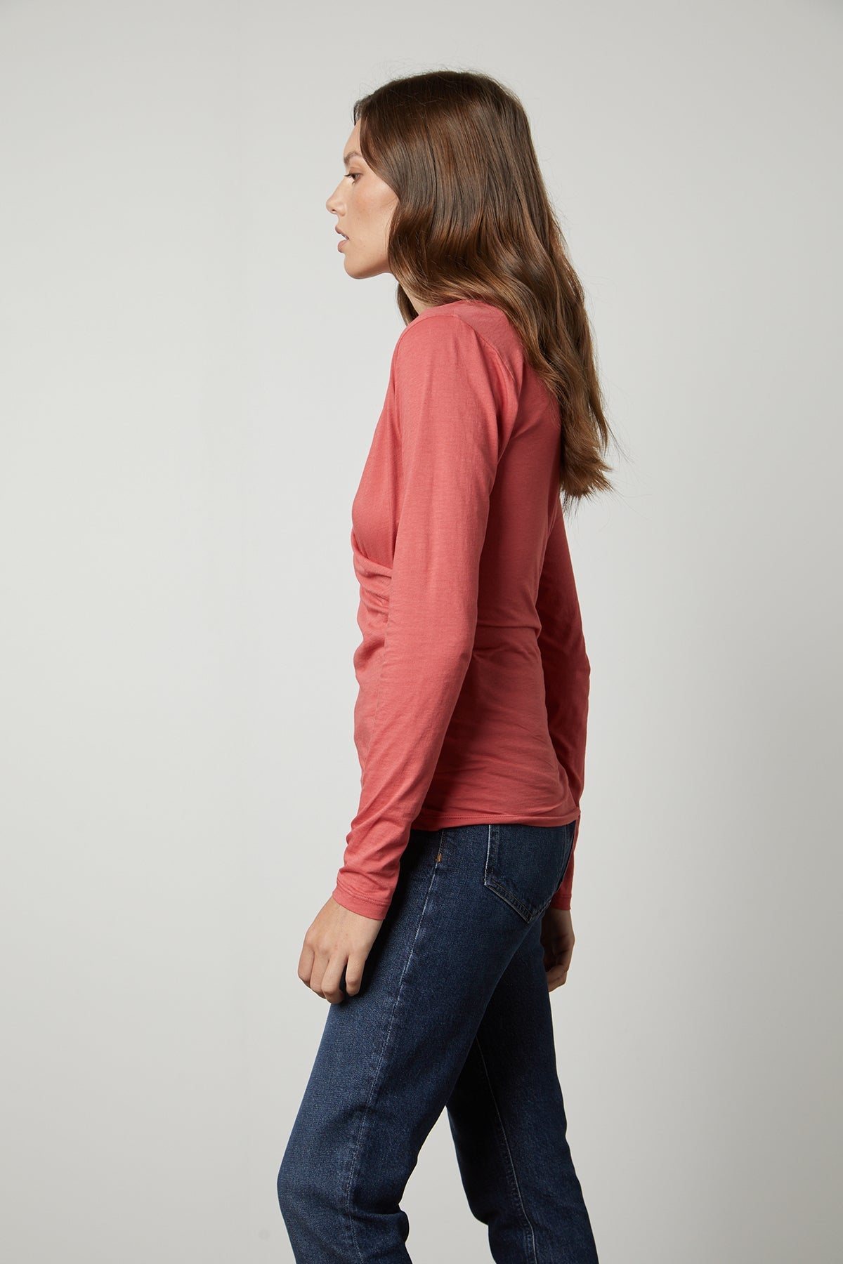   A woman wearing jeans and a long-sleeved MERI WRAP FRONT FITTED TOP by Velvet by Graham & Spencer. 