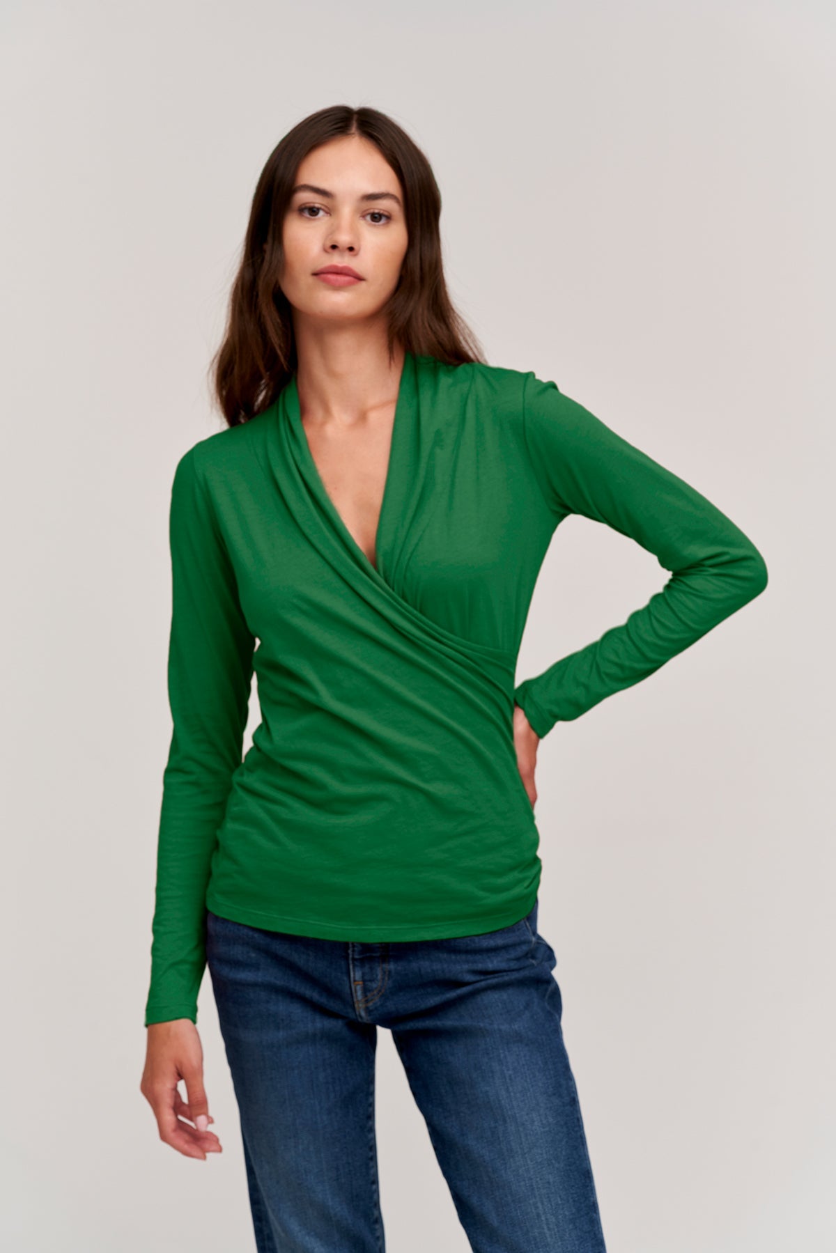 A woman wearing a Velvet by Graham & Spencer MERI Wrap Front Fitted Top and jeans.-26630826590401