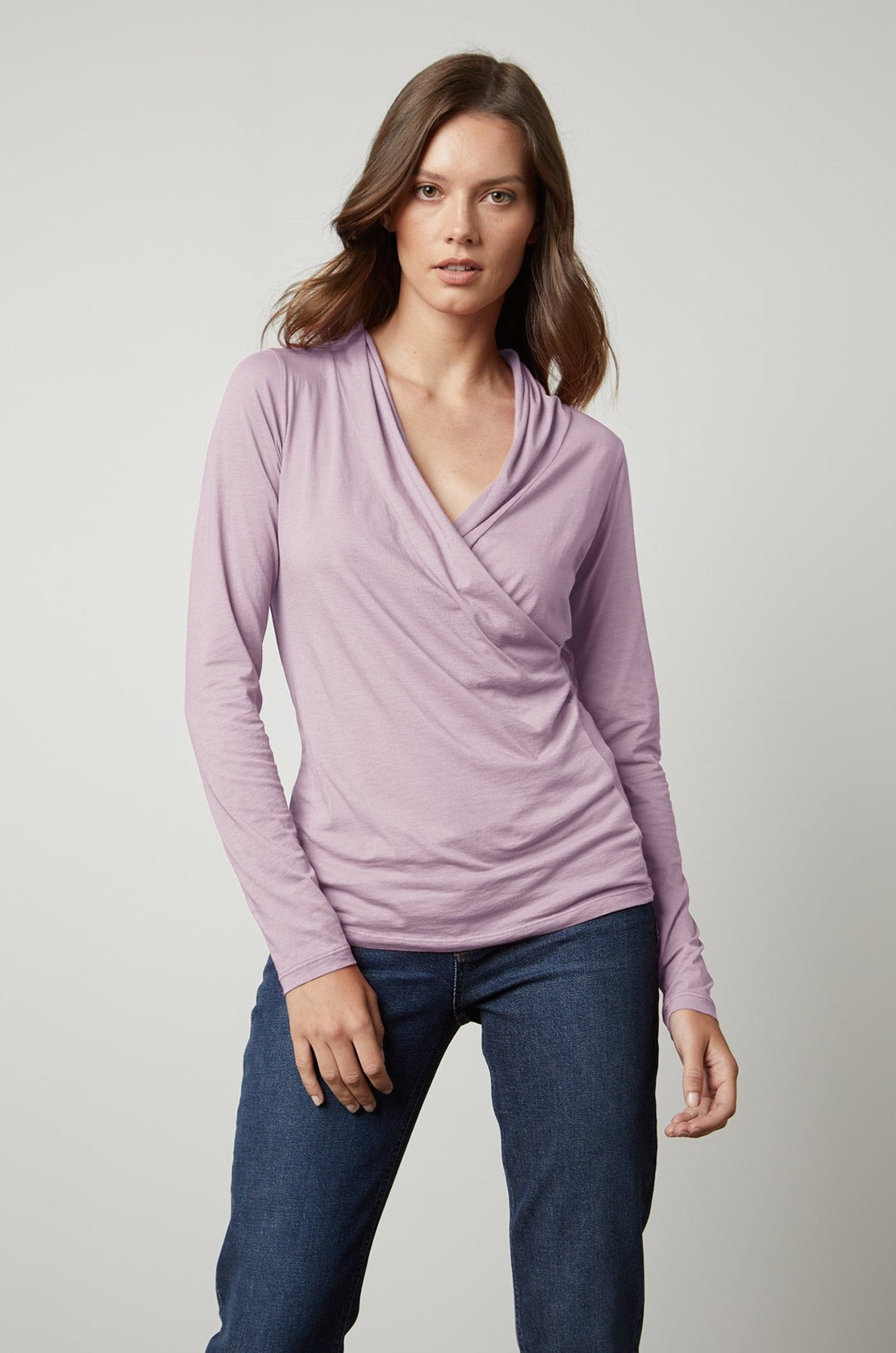 a woman wearing jeans and a Velvet by Graham & Spencer long-sleeved MERI WRAP FRONT FITTED TOP.-26630825410753