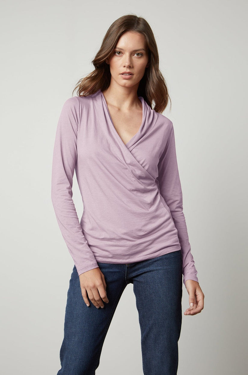 a woman wearing jeans and a Velvet by Graham & Spencer long-sleeved MERI WRAP FRONT FITTED TOP.