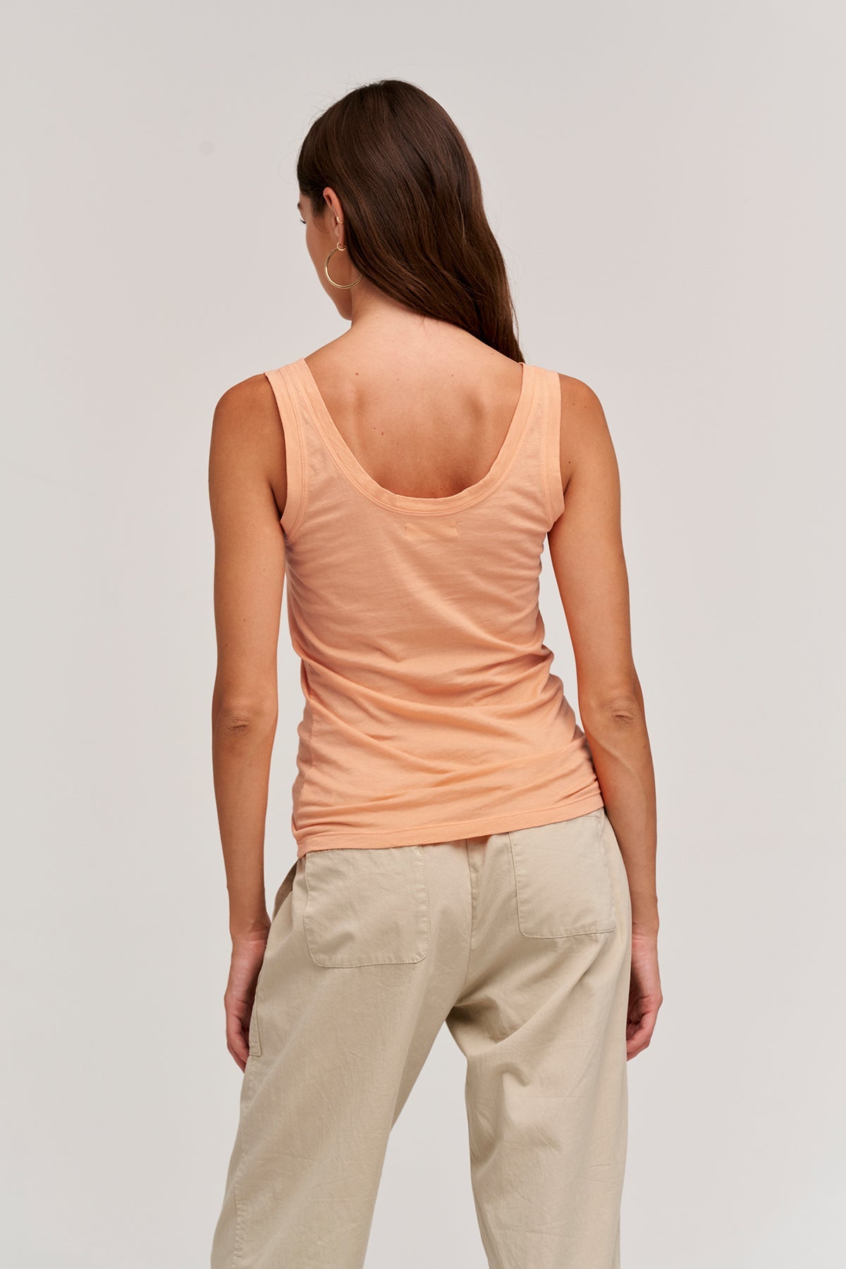   The back view of a woman wearing a Velvet by Graham & Spencer MOSSY GAUZY WHISPER FITTED TANK and tan pants. 