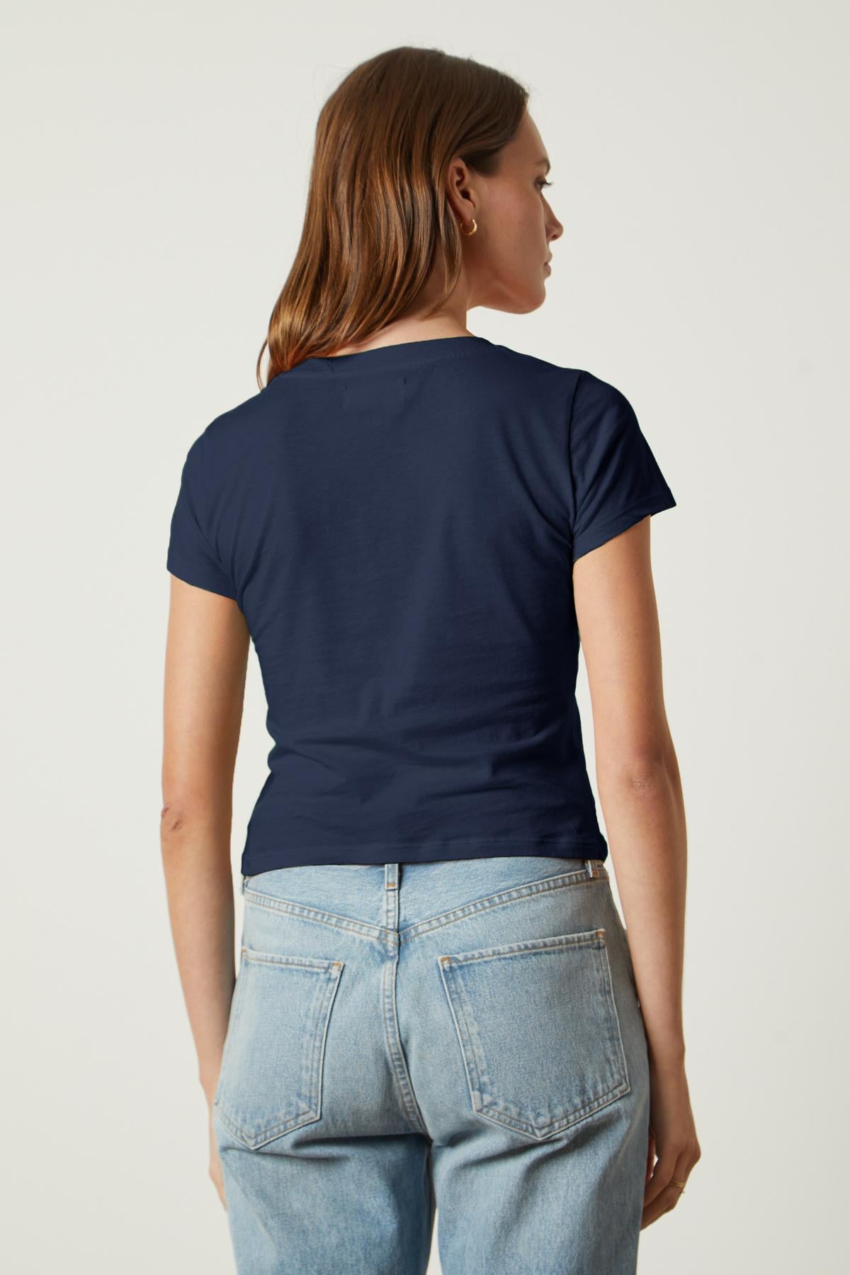   A woman wearing jeans and a navy Velvet by Graham & Spencer NINA CROPPED CREW NECK TEE, giving a sartorial throwback. 