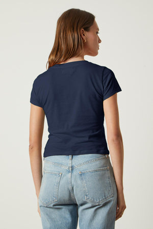 A woman wearing jeans and a navy Velvet by Graham & Spencer NINA CROPPED CREW NECK TEE, giving a sartorial throwback.
