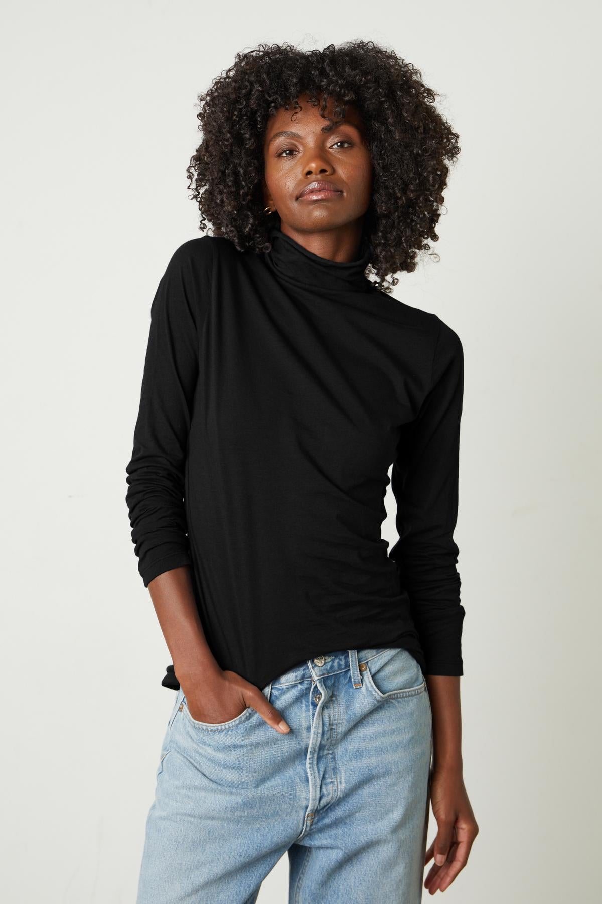   A woman donning a black TALISIA GAUZY WHISPER FITTED MOCK NECK TEE - a fashion staple in the wardrobe world, brought to you by Velvet by Graham & Spencer. 