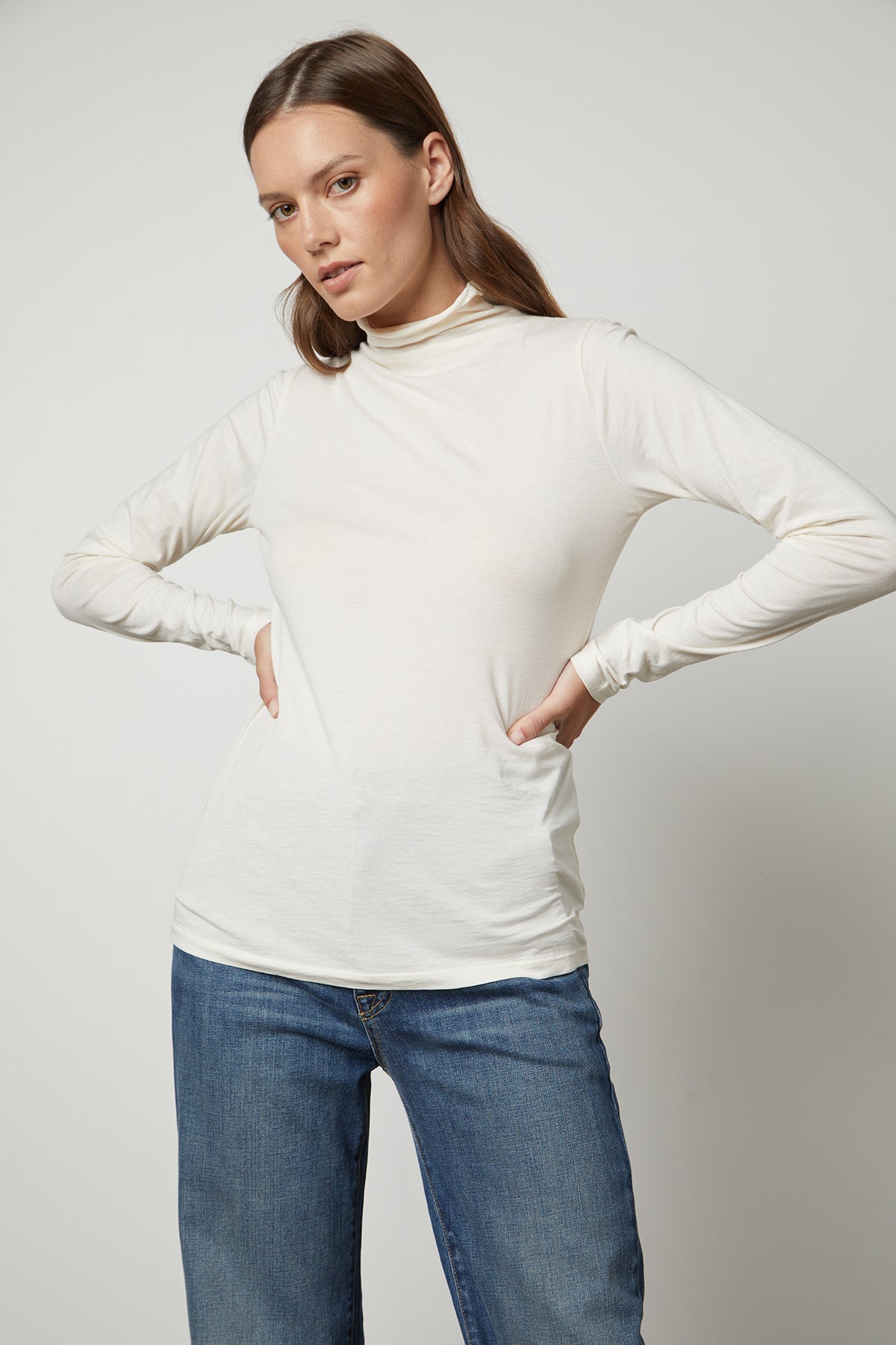 The model is wearing a TALISIA GAUZY WHISPER FITTED MOCK NECK TEE, a wardrobe staple in the fashion world by Velvet by Graham & Spencer.-35230354145473
