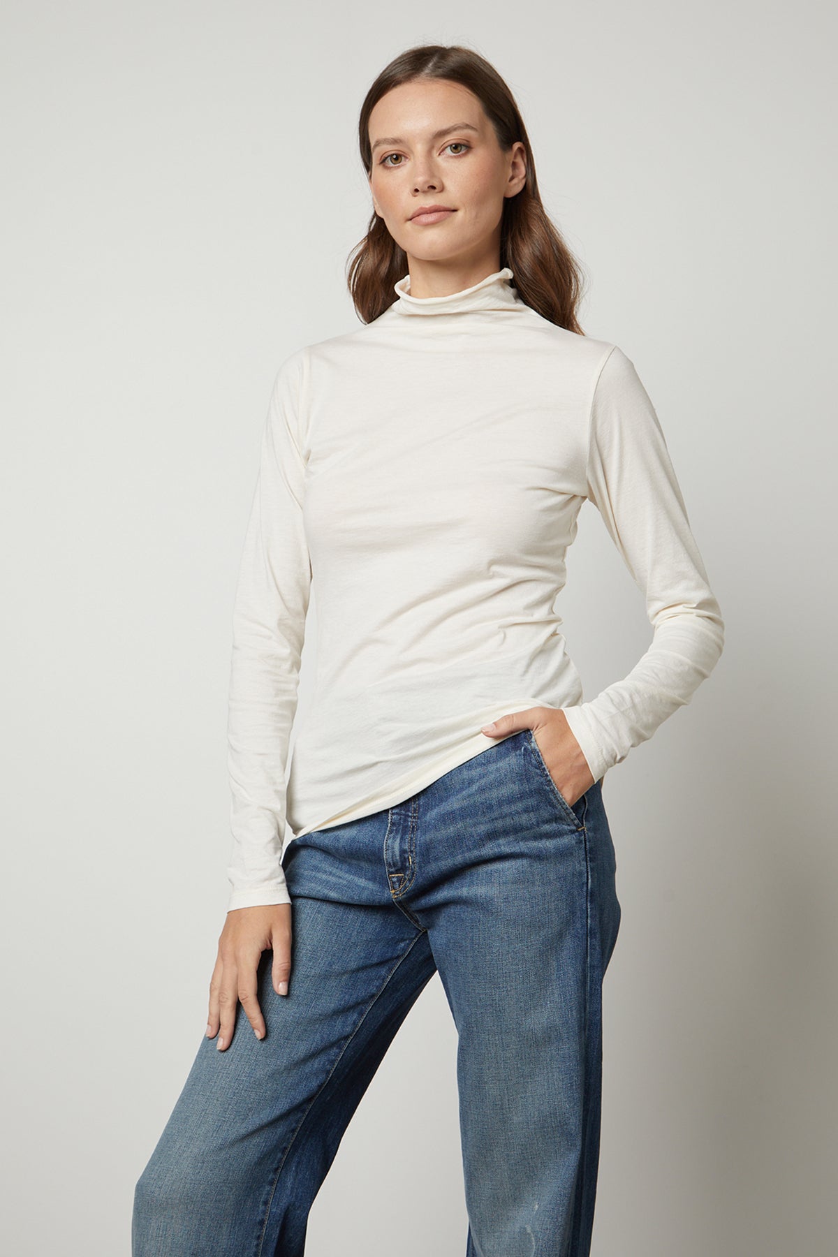 The model is wearing a Velvet by Graham & Spencer TALISIA GAUZY WHISPER FITTED MOCK NECK TEE, a wardrobe staple in the fashion world.-35230354079937