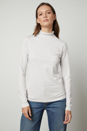 A woman wearing a Velvet by Graham & Spencer TALISIA GAUZY WHISPER FITTED MOCK NECK TEE is admired in the fashion world.