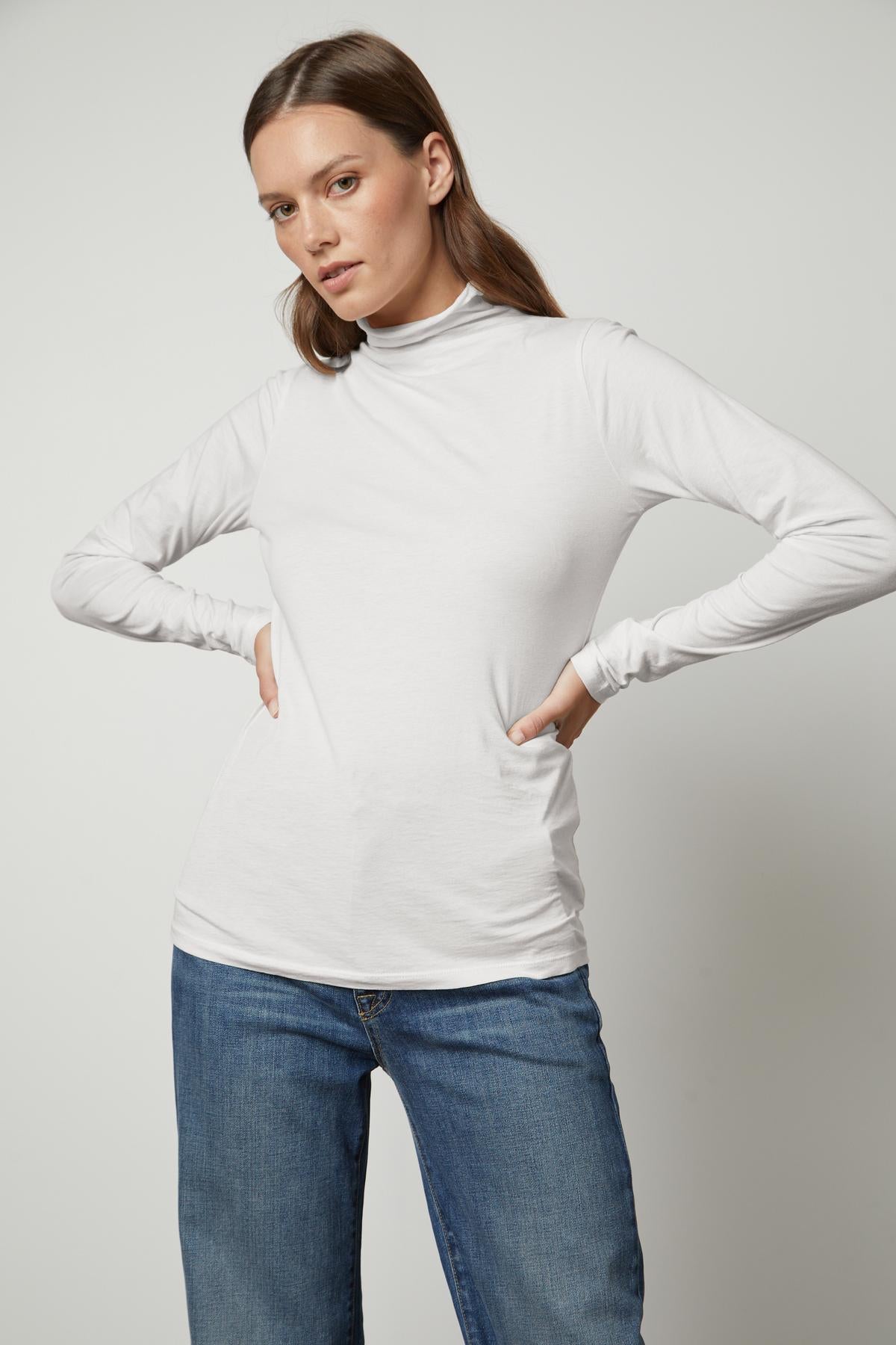   The model is wearing a white TALISIA GAUZY WHISPER FITTED MOCK NECK TEE by Velvet by Graham & Spencer. 