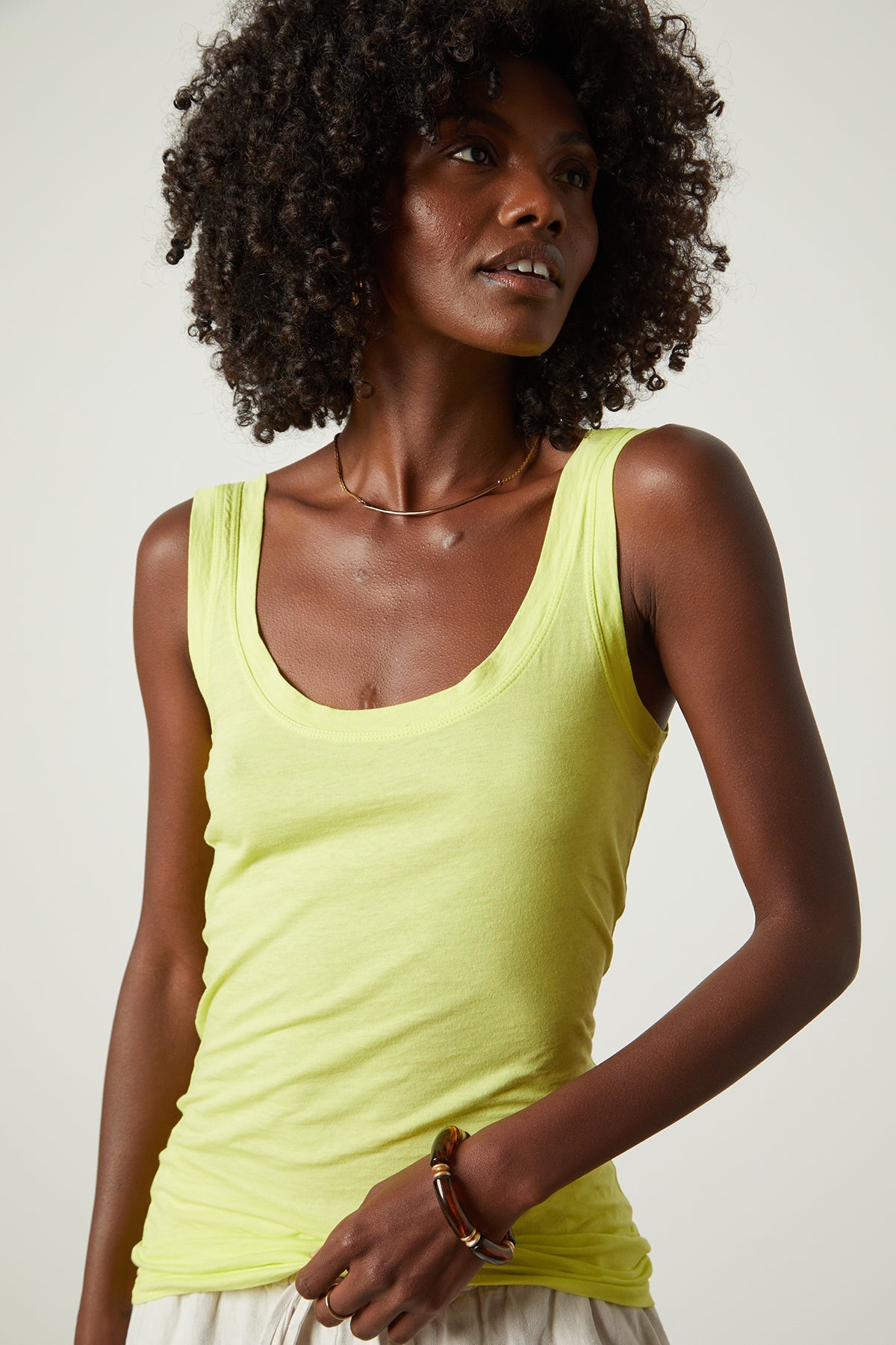   A woman wearing a Velvet by Graham & Spencer MOSSY GAUZY WHISPER FITTED TANK in yellow and white shorts. 