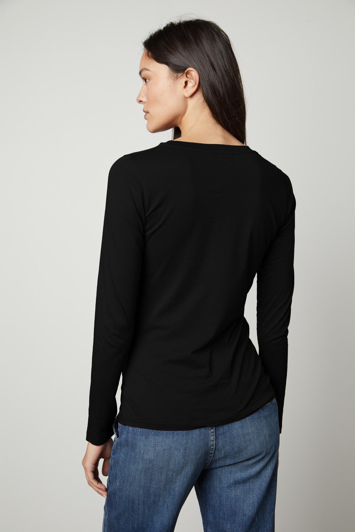 The back view of a woman wearing a Velvet by Graham & Spencer ZOFINA GAUZY WHISPER FITTED CREW NECK TEE.-35503491186881