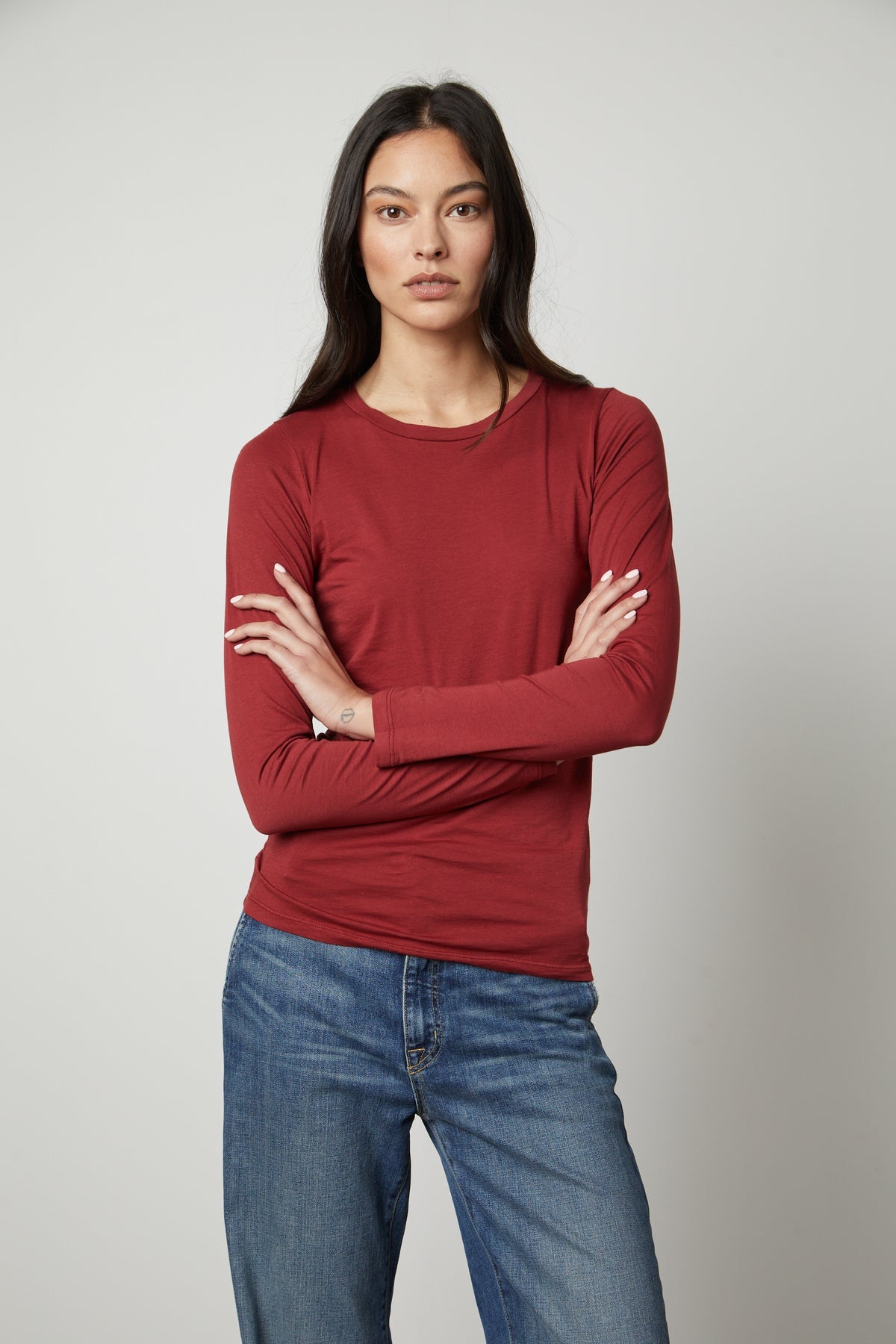 A woman wearing a ZOFINA GAUZY WHISPER FITTED CREW NECK TEE by Velvet by Graham & Spencer, which has a universally flattering cut and is red with long sleeves.-35783263158465
