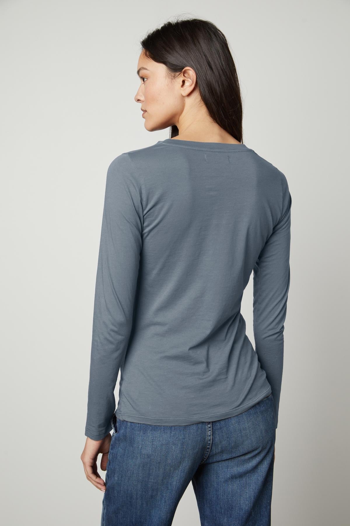 The back view of a woman wearing a Velvet by Graham & Spencer ZOFINA GAUZY WHISPER FITTED CREW NECK TEE.-35783262273729