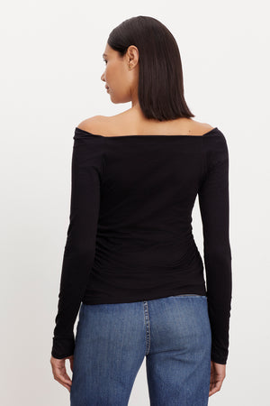 The back view of a woman wearing a Velvet by Graham & Spencer ALISS FITTED TEE off-shoulder top.