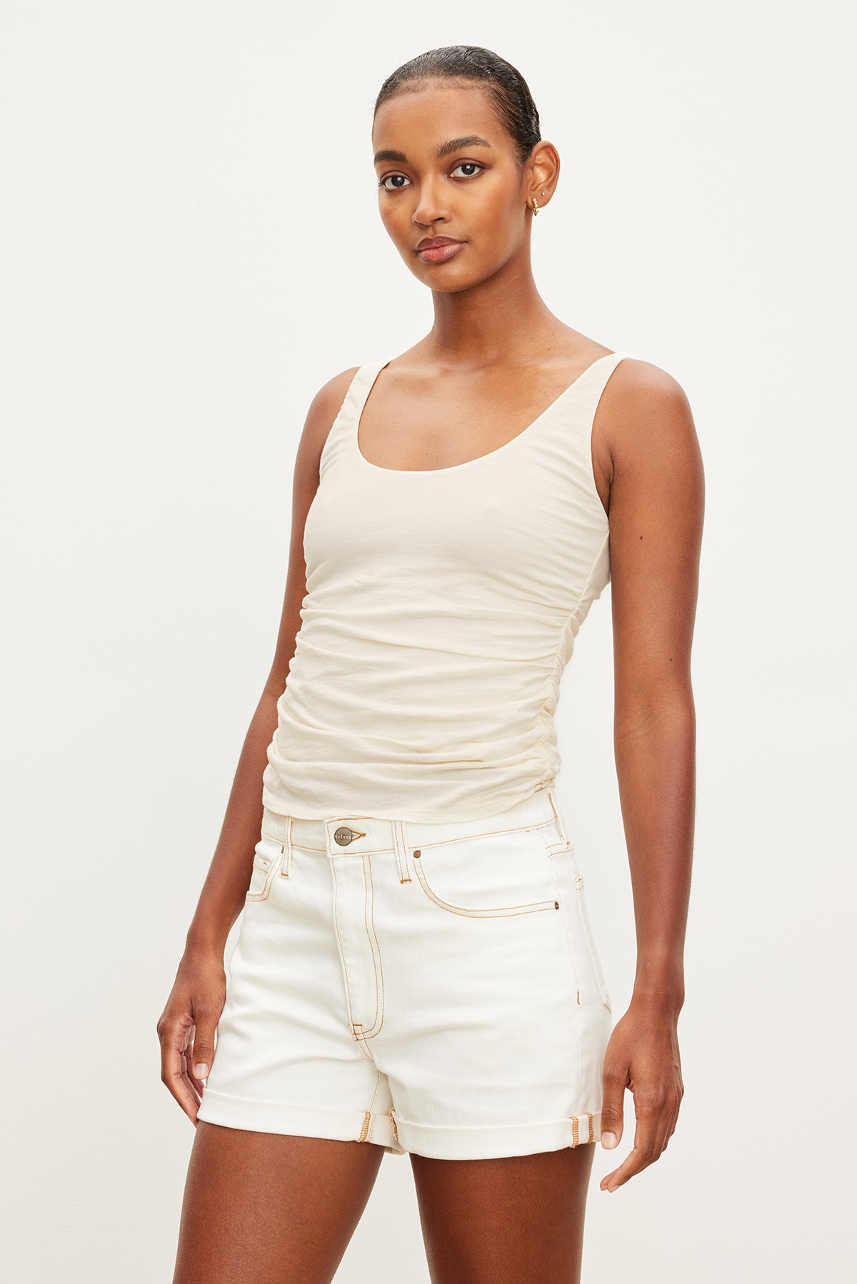   The model is wearing a Velvet by Graham & Spencer DRUCIE SCOOP NECK TANK TOP and white shorts. 