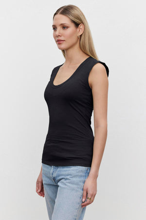 A woman in a Velvet by Graham & Spencer ESTINA GAUZY WHISPER FITTED TANK TOP and jeans.