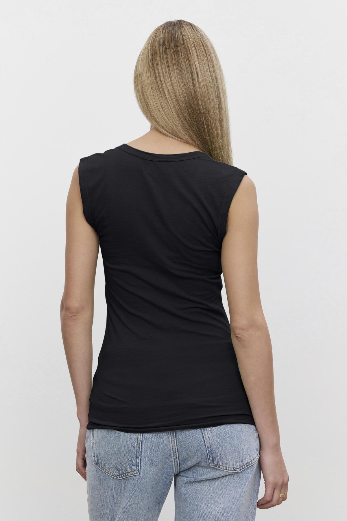 A woman in a Velvet by Graham & Spencer ESTINA GAUZY WHISPER FITTED TANK TOP with a low-scoop-neck.-36266808377537