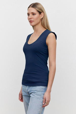 A woman wearing a Velvet by Graham & Spencer ESTINA GAUZY WHISPER FITTED TANK TOP and jeans with a low-scoop-neck.