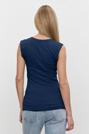 The woman is wearing blue jeans and a Velvet by Graham & Spencer ESTINA GAUZY WHISPER FITTED TANK TOP.