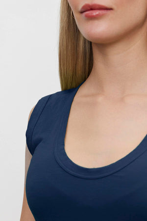 A woman in a Velvet by Graham & Spencer ESTINA GAUZY WHISPER FITTED TANK TOP with a low-scoop-neck.