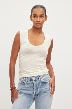 A woman wearing a Velvet by Graham & Spencer ESTINA GAUZY WHISPER FITTED TANK TOP and blue jeans.