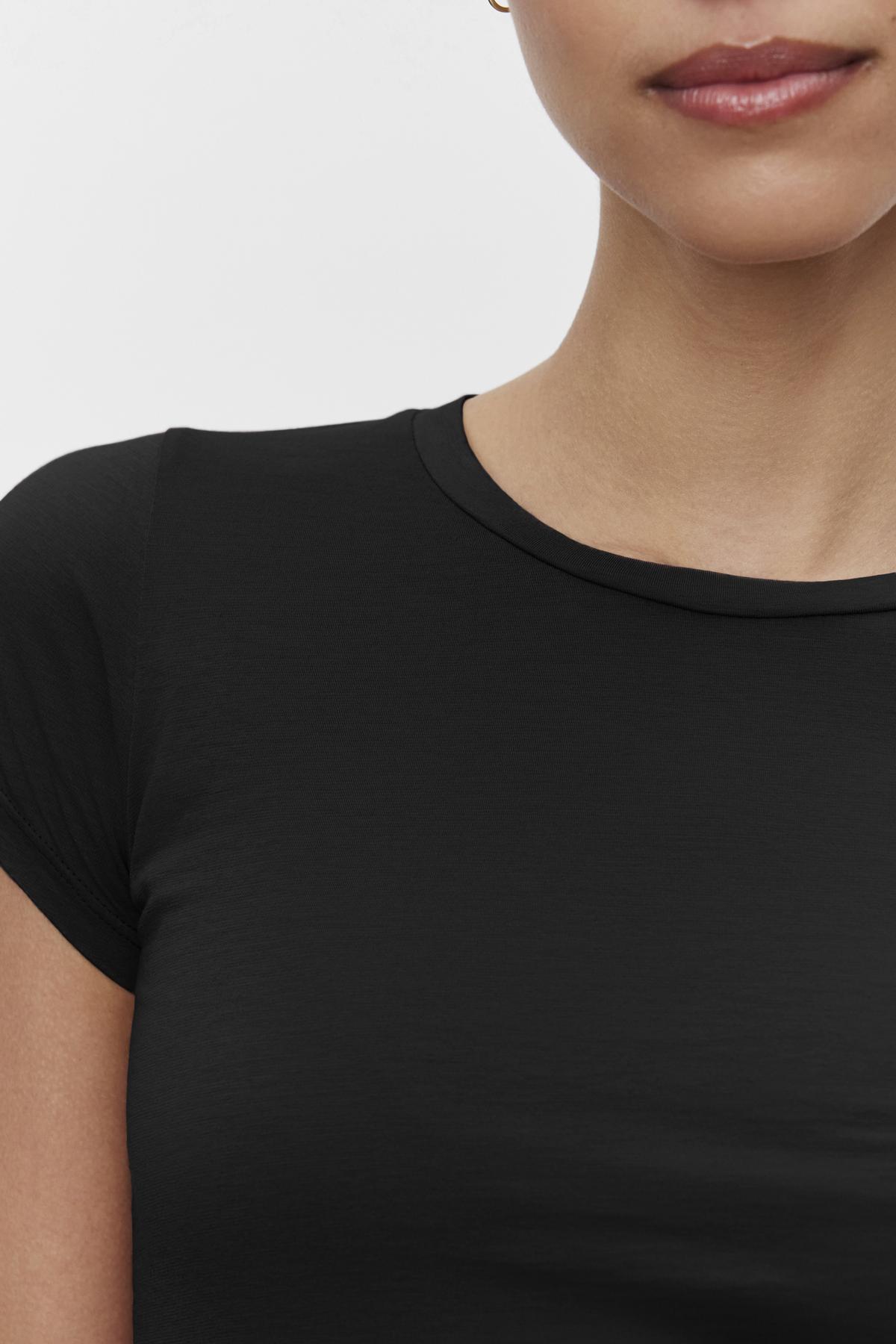   A cropped image of a person wearing the JEMMA TEE, a timeless staple by Velvet by Graham & Spencer, against a white background, showing from the lips to the upper chest. 