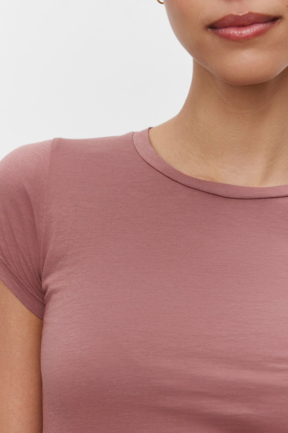   Close-up image of a person wearing an ultra-soft gauzy whisper mauve Velvet by Graham & Spencer JEMMA TEE, focusing on the upper torso and part of the face with minimal details visible. 