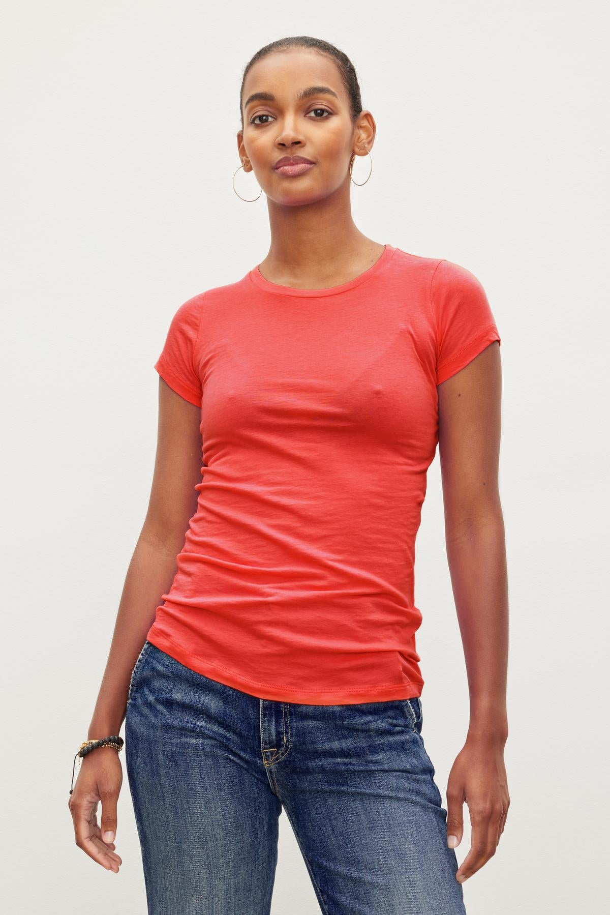 A woman wearing a Velvet by Graham & Spencer JEMMA GAUZY WHISPER FITTED CREW NECK TEE and jeans.-36002770485441