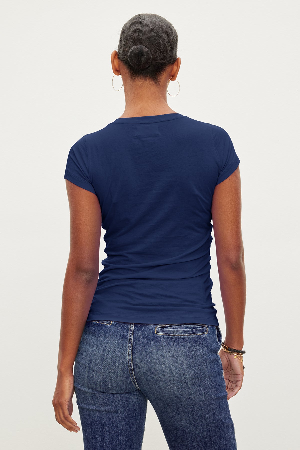 The back view of a woman wearing jeans and a Velvet by Graham & Spencer JEMMA GAUZY WHISPER FITTED CREW NECK TEE.-35571890847937