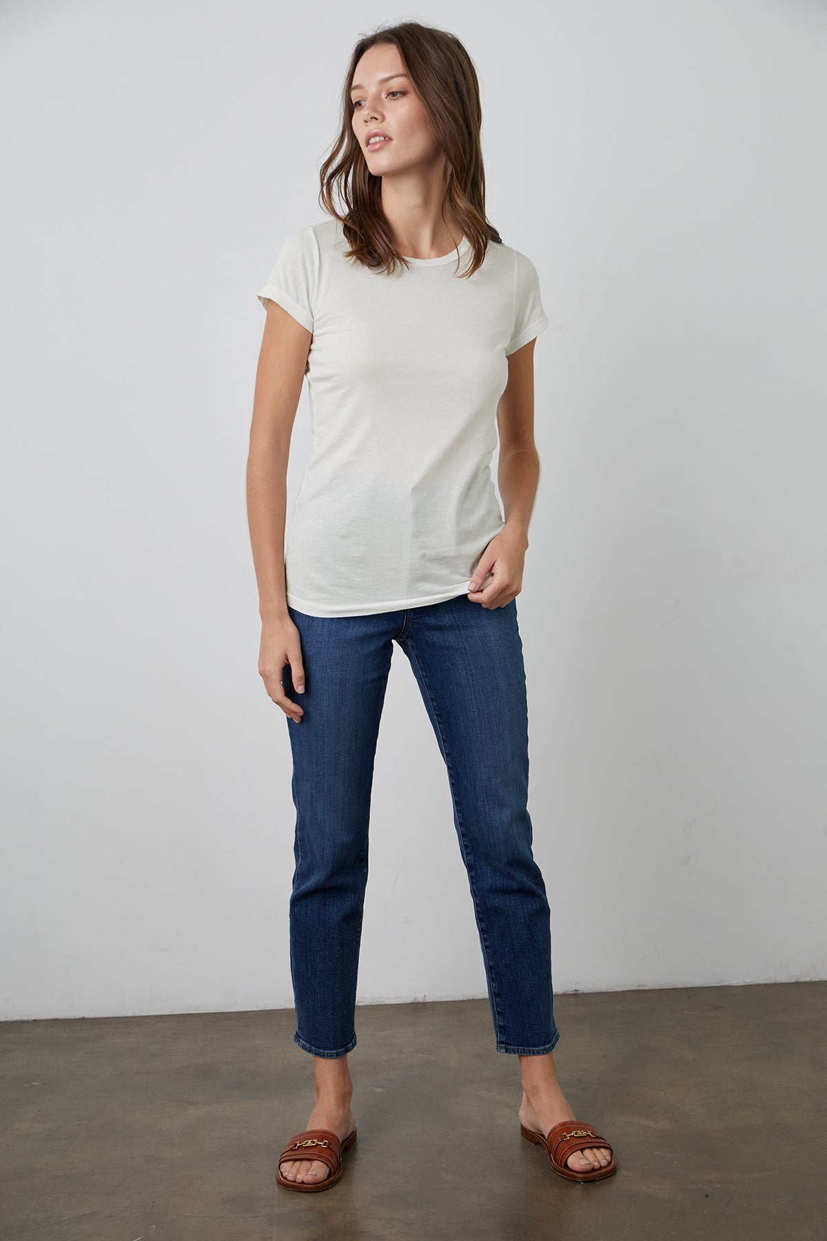   The model is wearing a JEMMA GAUZY WHISPER FITTED CREW NECK TEE by Velvet by Graham & Spencer and blue jeans. 