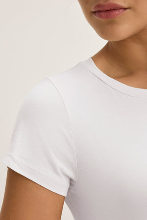 Close-up of a woman wearing the JEMMA TEE by Velvet by Graham & Spencer, highlighting the ultra-soft crew neck, her neck, shoulder, and part of her face against a neutral background.