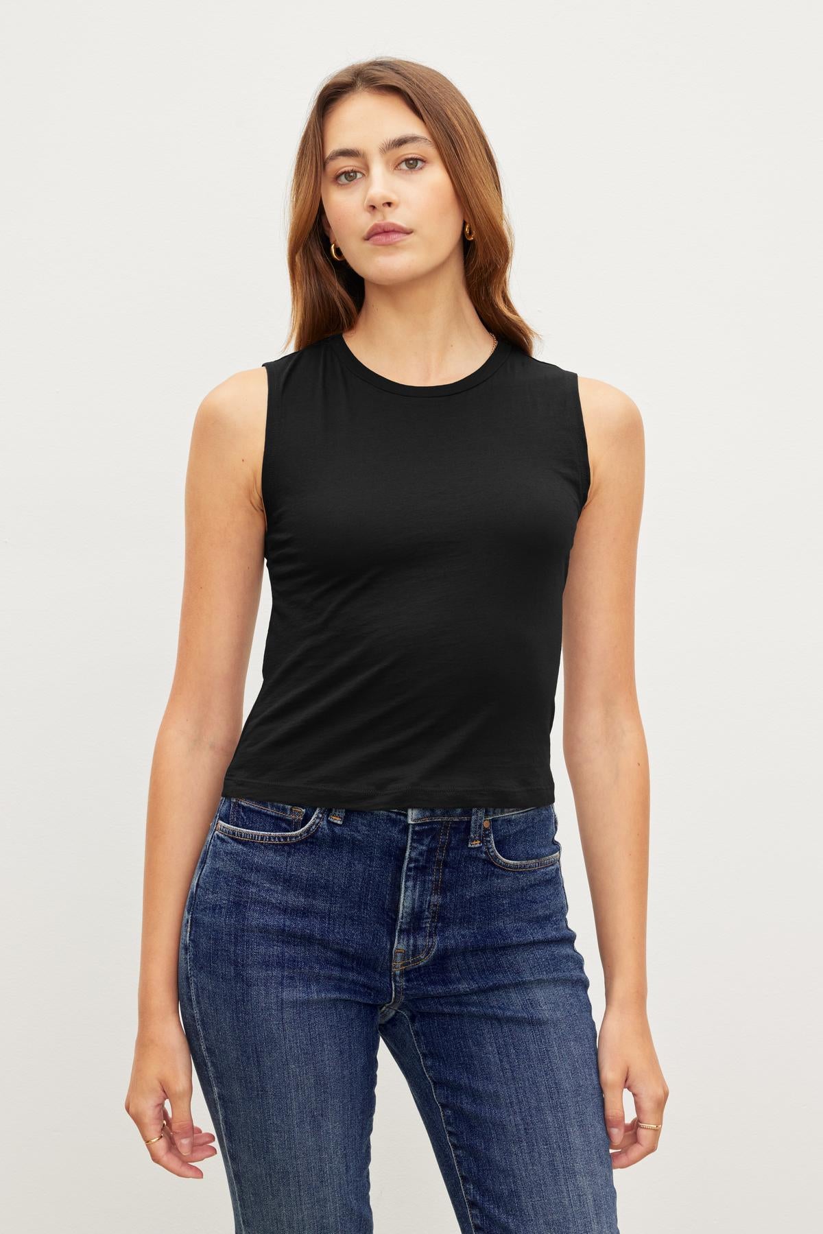 Woman standing against a plain background, wearing a Velvet by Graham & Spencer MAGSON CREW NECK TANK TOP and blue jeans, looking directly at the camera.-36418284421313