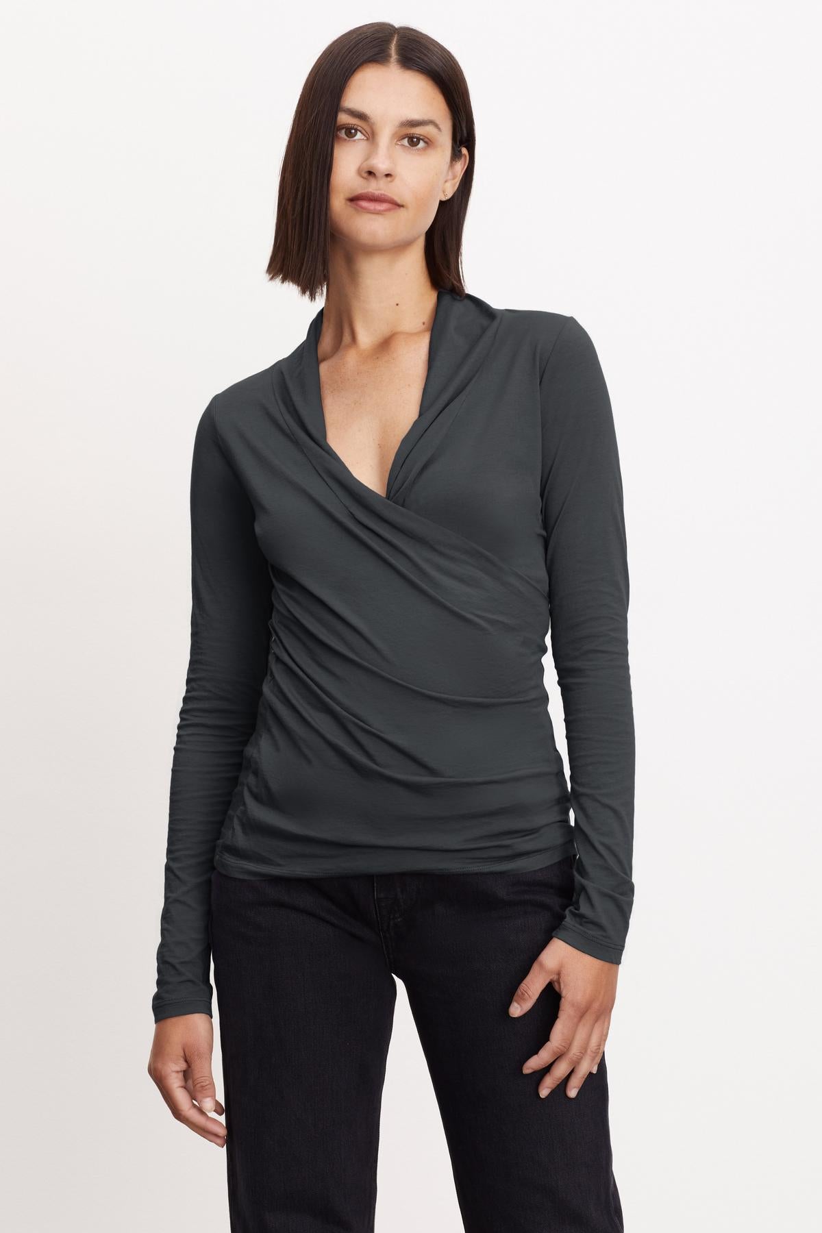   A woman wearing a Velvet by Graham & Spencer MERI WRAP FRONT FITTED TOP, grey long-sleeved top. 