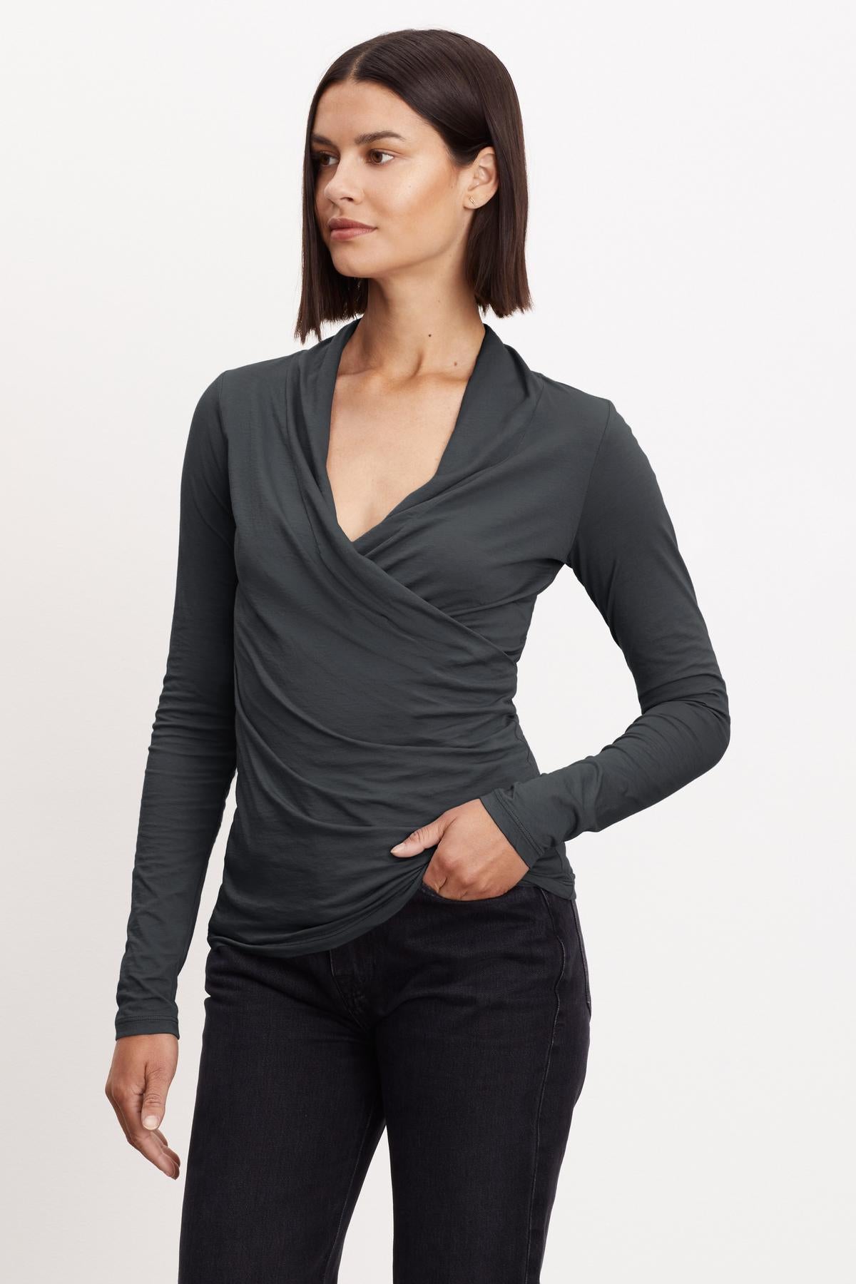   A woman wearing a Velvet by Graham & Spencer MERI WRAP FRONT FITTED TOP, a grey long-sleeved top with a slight crossover v-neck. 