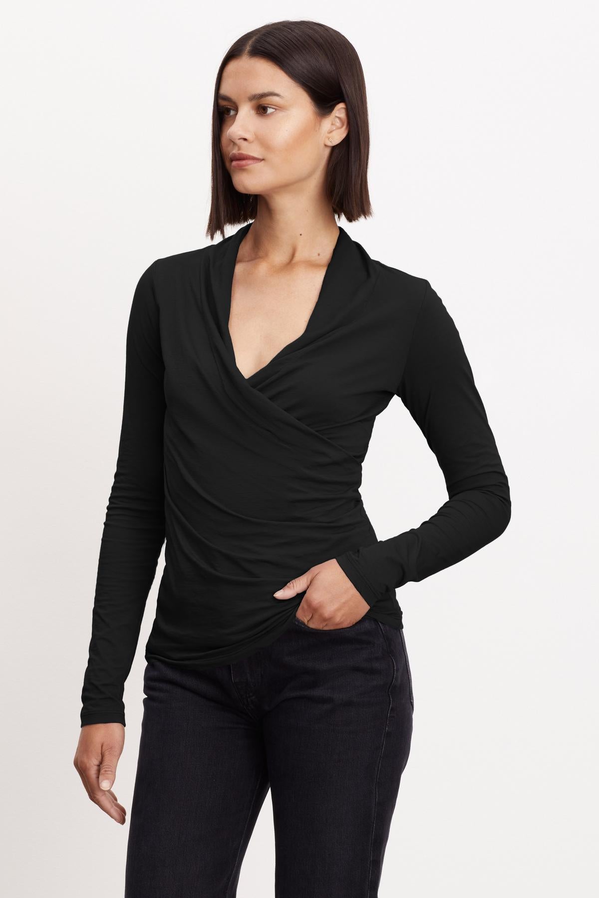 A woman wearing a black long-sleeved Velvet by Graham & Spencer MERI Wrap Front Fitted Top with clean lines.-26921359376577