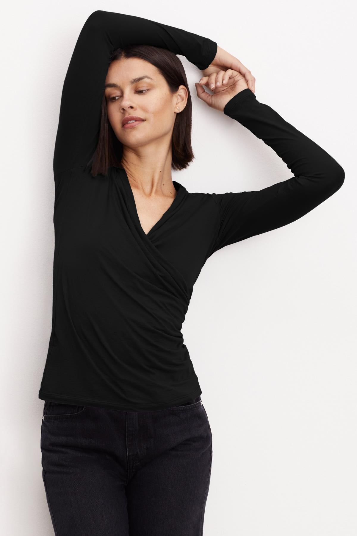 A woman wearing a Velvet by Graham & Spencer MERI WRAP FRONT FITTED TOP in classic black with clean lines.-26921359409345
