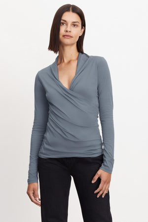 The model is wearing a Velvet by Graham & Spencer MERI WRAP FRONT FITTED TOP gray long-sleeved top with cross-over v-neck.