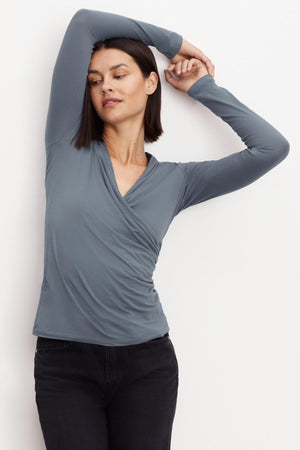 A woman wearing a Velvet by Graham & Spencer MERI WRAP FRONT FITTED TOP, a fitted, grey long-sleeved top with a cross over v-neck.